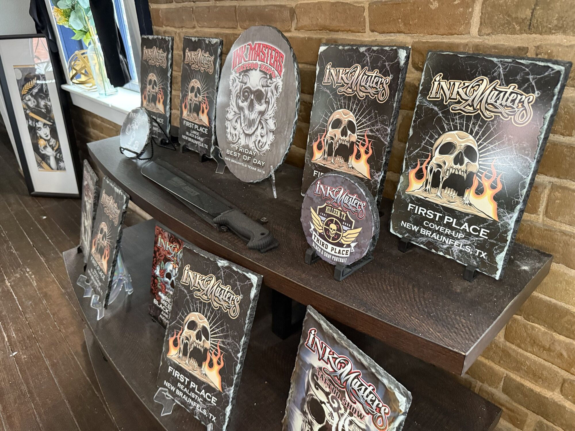 Tattoo convention awards on a shelf at Lions Den, including First Place, Cover-Up, New Braunfels, Texas.