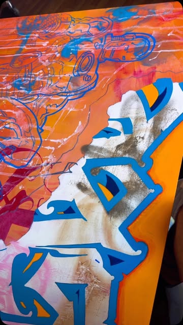 A painting in bright orange, cobalt blue and white, with layered lettering forms.