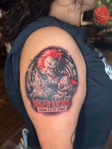 A full color tattoo on an upper arm, showing a clown character framed in a circle.
