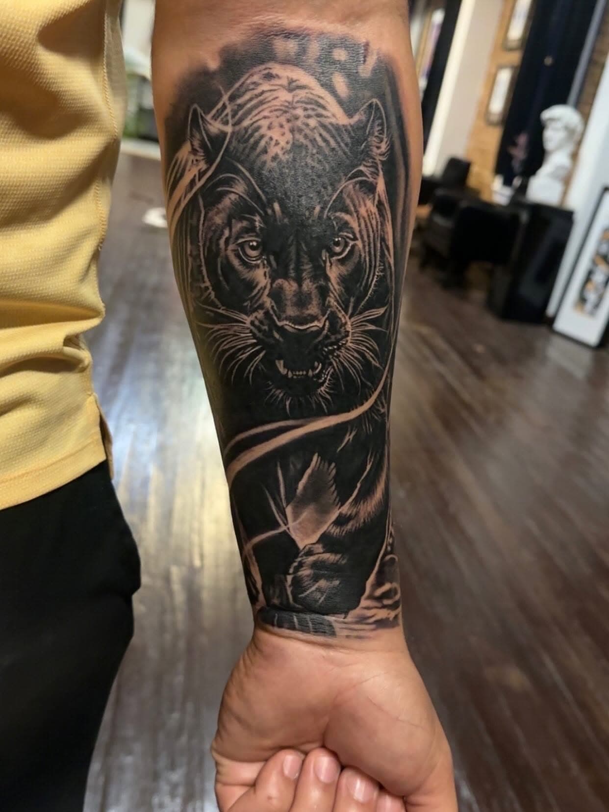 A black and grey panther tattoo on a forearm, its face looking straight ahead.